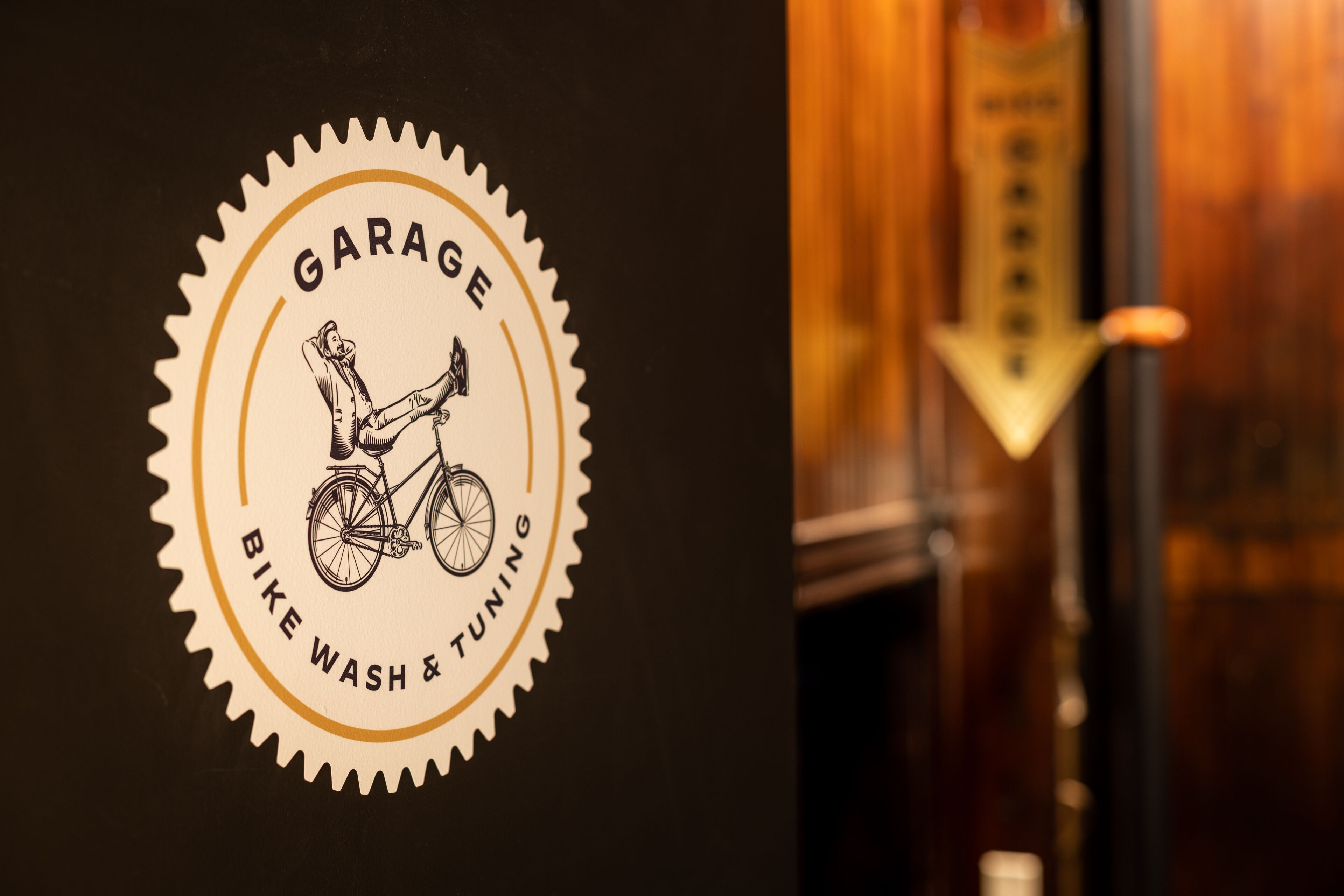 Ein Logo mit einem Fahrrad und dem Text 'Garage Bike Wash & Tuning' vor dunklem Hintergrund.