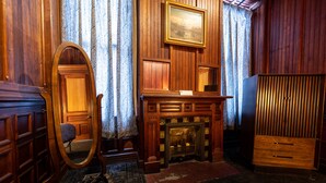 A room with wooden paneling, a fireplace, a mirror, and a wardrobe. - Traveler's Rest Hotel (Pittsburgh)