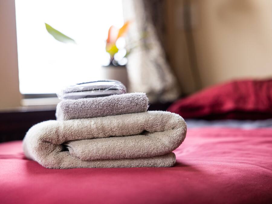 Un montón de toallas dobladas sobre una cama con cubrecolor rojo.