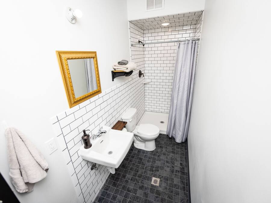 A bathroom with a white sink, a toilet, a shower with a curtain, and a mirror with a gold frame.