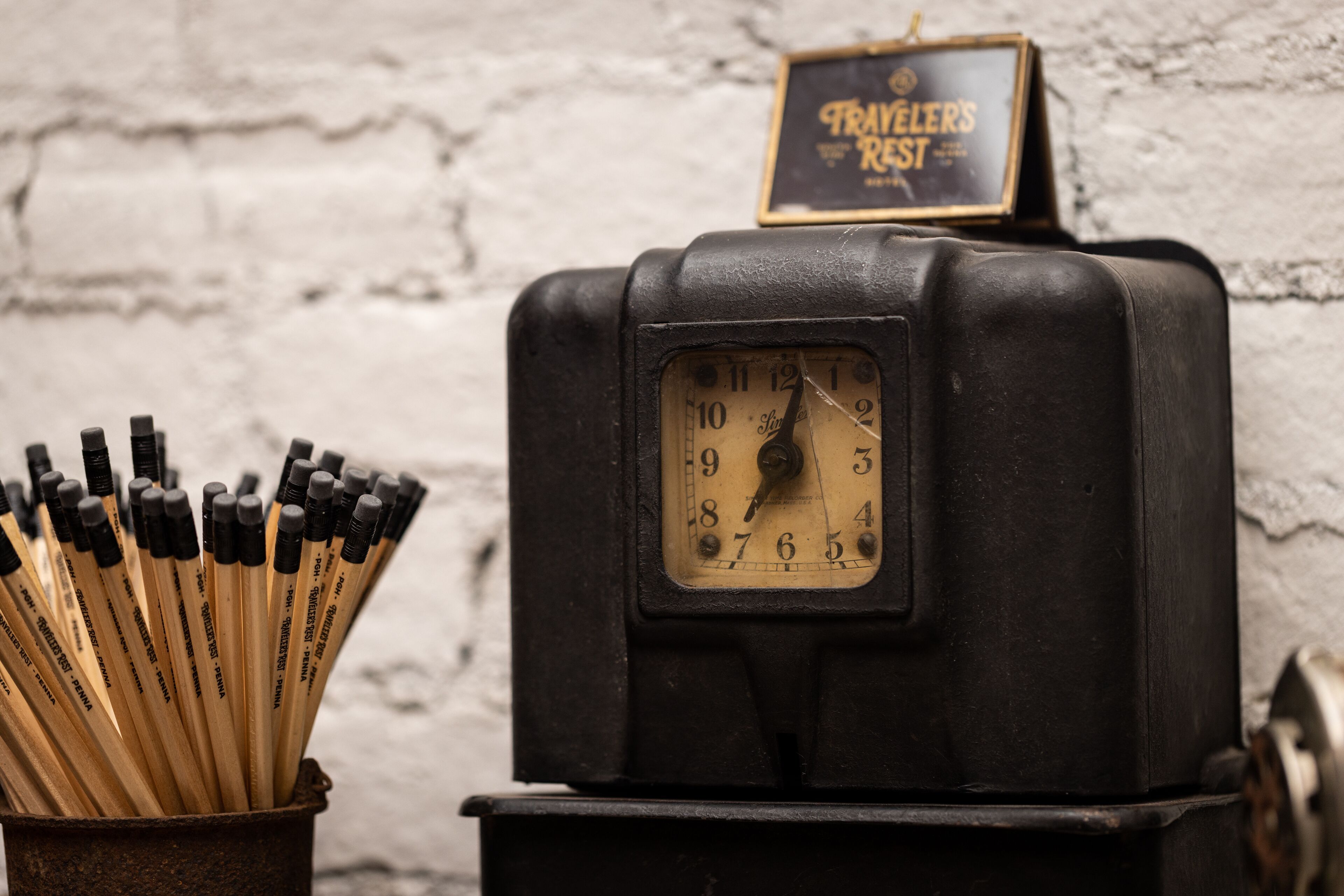 A vintage black clock with a sign above it that reads "TRAVELER'S REST".