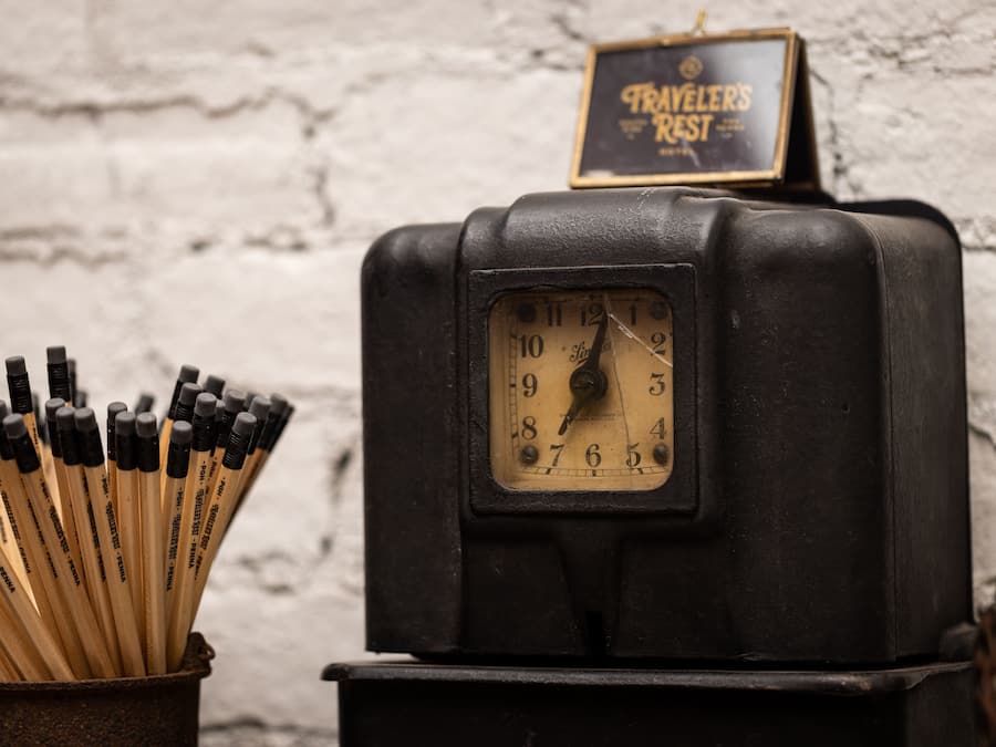 A vintage black clock with a sign above it that reads "TRAVELER'S REST".