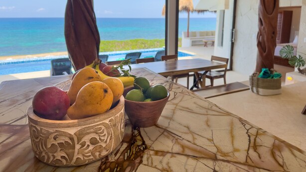A table with fruit and a view of the ocean.