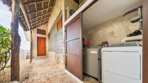 A laundry area with a washing machine and dryer, a wooden door, and a stone wall.