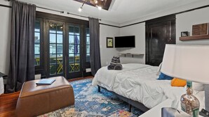 A modern hotel room with a large bed, a desk, a chair, a TV, and a view through the glass doors. - This gem sits in the heart of picturesque South Frankfort, near the Kentucky river (Frankfort)