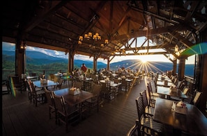 An outdoor dining area with tables and chairs, wooden beams, and a view of the mountains. - Walk to Downtown Gatlinburg, 3 En-Suite Bedrooms, Creekside with Pool (Gatlinburg)