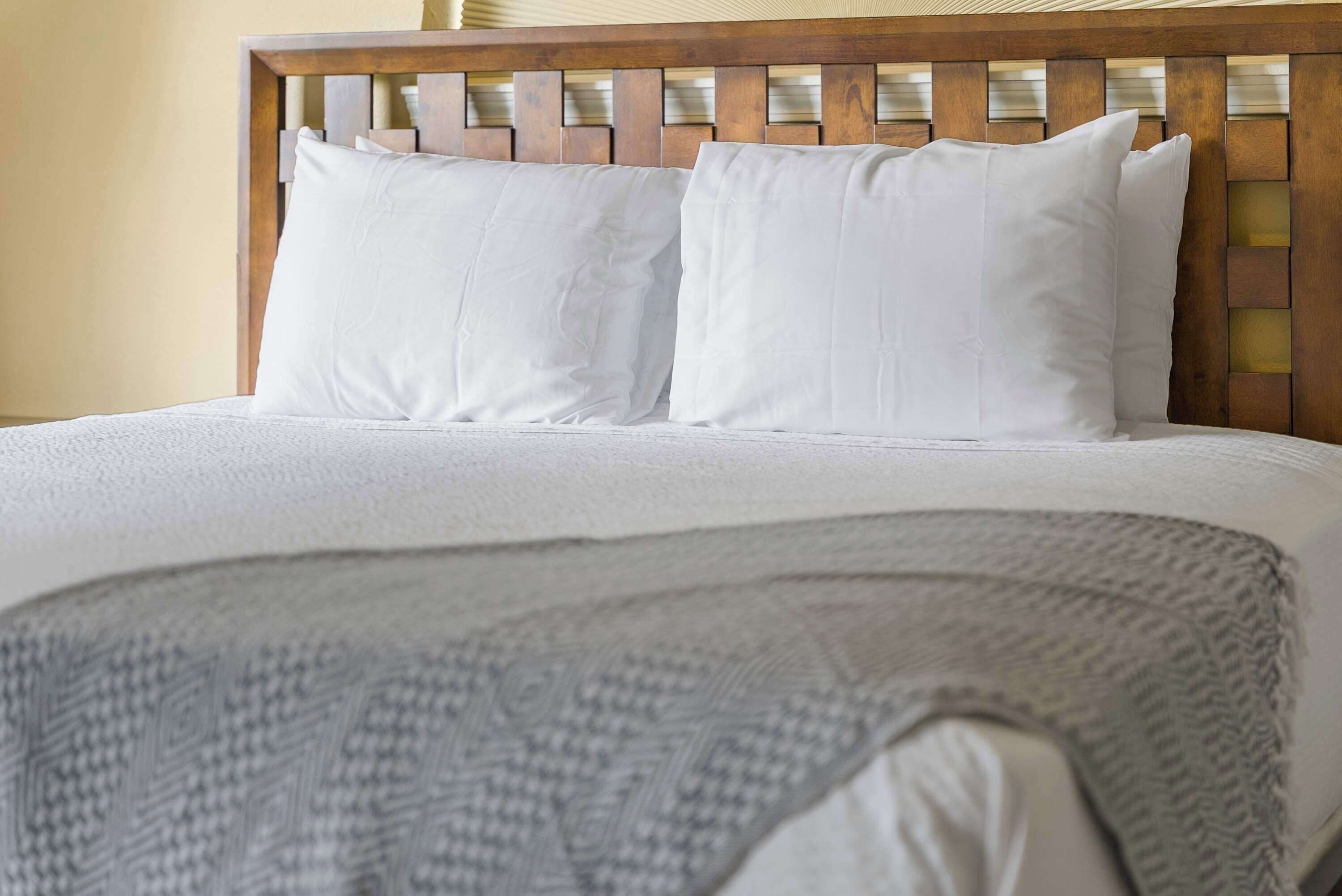 A bed with white bedding and a wooden headboard.