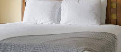 A bed with white bedding and a wooden headboard.