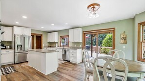 Een moderne keuken met witte kasten, een centraal eiland en een zithoek met een houten tafel en stoelen.