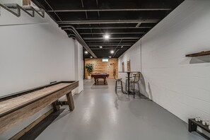 A narrow hallway with a billiards table, stools, and a potted plant. - Deer Run Manor - Indoor Pool, Hot Tub & Game Room (Rockbridge)