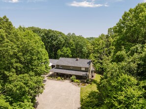 A two-story house with a front porch, surrounded by dense green trees. - Deer Run Manor - Indoor Pool, Hot Tub & Game Room (Rockbridge)