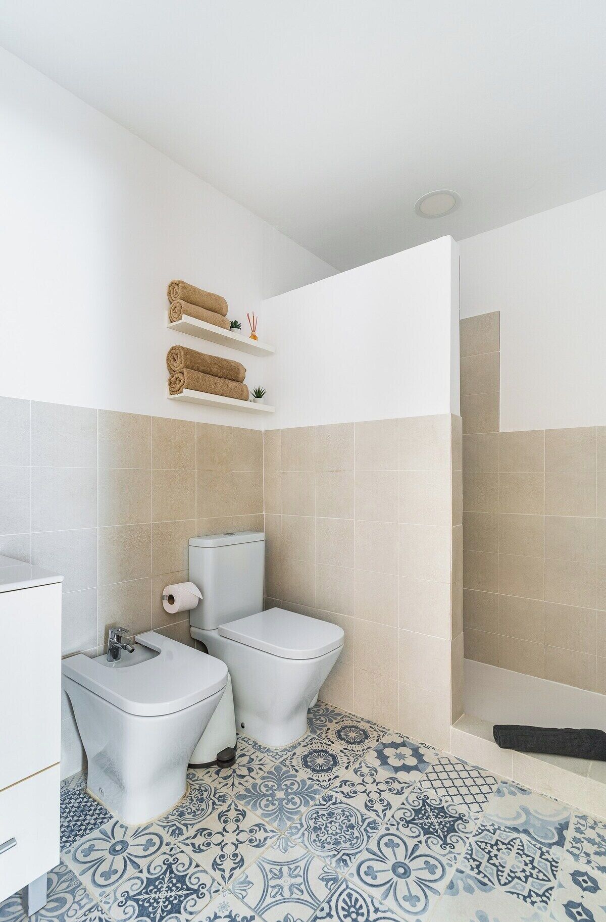 A bathroom with two toilets, a sink, and a shower area.