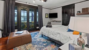 Ein modernes Hotelzimmer mit Bett, Schreibtisch, Stuhl, Fernseher und einem Fenster mit Vorhängen.