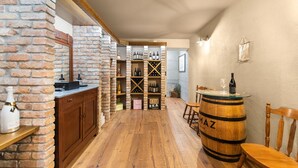 Ein schmaler Flur mit Holzboden, einer Backsteinwand und einem Weinkühlschrank, gefüllt mit Flaschen.