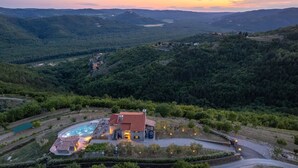 Eine Villa mit Swimmingpool, umgeben von üppiger Vegetation und Hügeln.