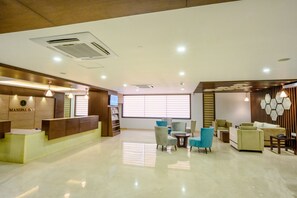A hotel lobby with a reception desk, seating area, and a large window providing natural light. - Ranjitha Palace (Manipal Inn) (Udupi)