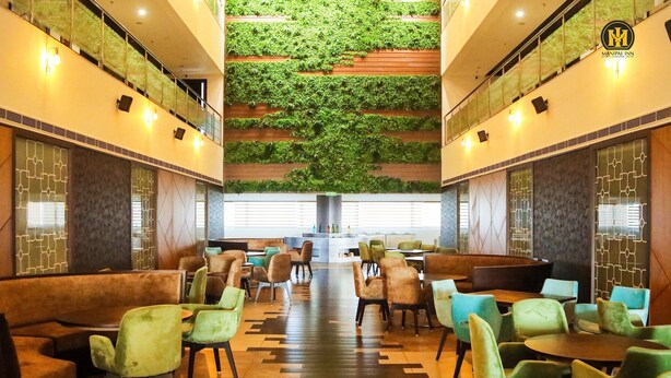 A restaurant with a central seating area, green plants on the walls, and a modern design. - Ranjitha Palace (Manipal Inn) (Udupi)