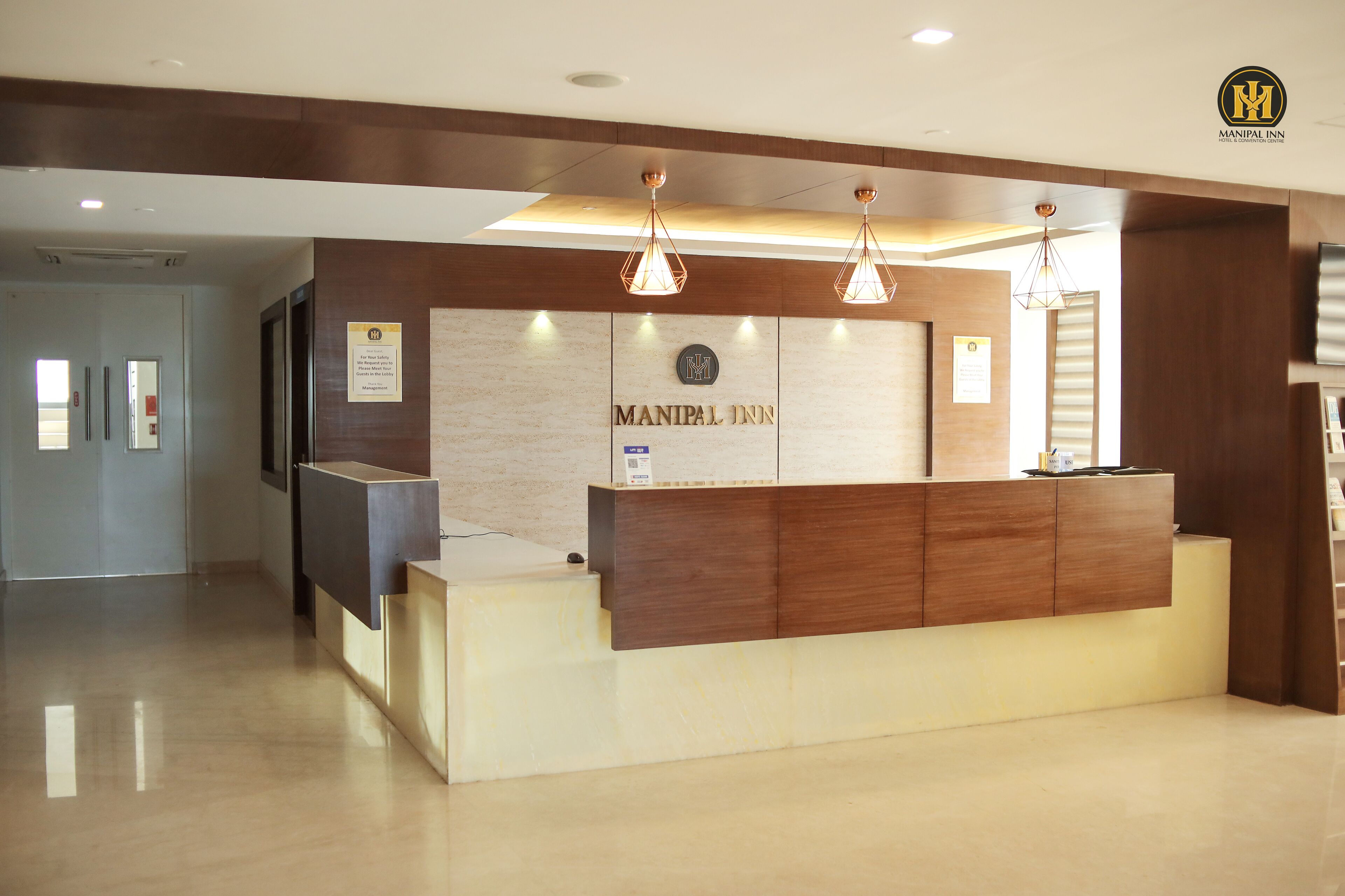 Un comptoir d’accueil avec un revêtement en bois et une enseigne indiquant « MANIPAL INN ».