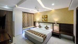 A modern hotel room with a large bed, bedside lamps, a ceiling fan, and a TV. - Ranjitha Palace (Manipal Inn) (Udupi)