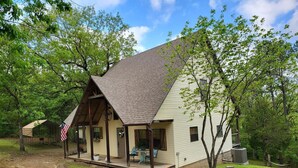 A two-story cabin with a porch, a covered outdoor seating area, and a small shed. - Wister Ridge Cottage • Sleeps 10 • 3 Minutes to Wister Lake! (Wister)