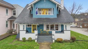 Ein zweistöckiges Haus mit einem Satteldach, einer Veranda mit gelben Türen und einem kleinen Vorgarten.