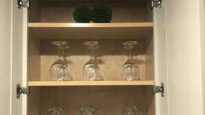 Un meuble avec trois étagères, chacune contenant différents types de verrerie.