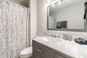 Un baño con lavamanos de mármol, un espejo grande y una cortina de ducha con estampado floral.