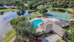 A residential area with a swimming pool, tennis courts, and a pond. - Entire House with Game Room in Lutz, Near Tampa and Wesley Chapel (Lutz)