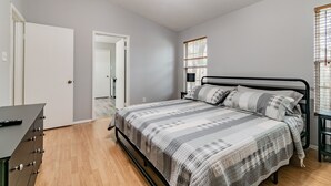 A bedroom with a bed, dresser, and a door leading to another room. - Entire House with Game Room in Lutz, Near Tampa and Wesley Chapel (Lutz)
