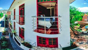 A two-story building with balconies, red-framed windows, and a curved roof. - Sumaq Wari Hotel (Ayacucho)