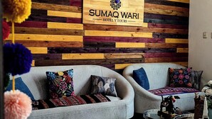 A modern hotel room with a wooden wall, two sofas, colorful cushions, and a decorative mirror. - Sumaq Wari Hotel (Ayacucho)
