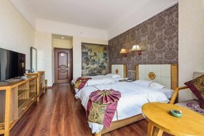 A hotel room with a wooden floor, a TV, a desk, two beds with headboards, and a painting on the wall.
