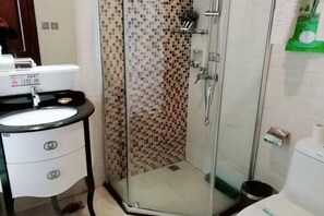 Un baño con cabina de ducha de vidrio, lavamanos con encimera negra y un inodoro.