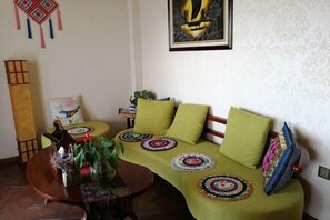 Una sala de estar con un sofá curvo, una mesa de centro de madera y una mesita auxiliar.