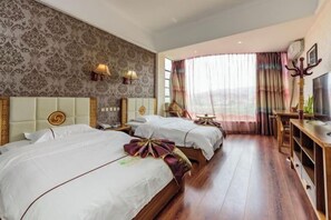 A hotel room with two beds, a wooden floor, a large window with curtains, and a television on a wooden stand.