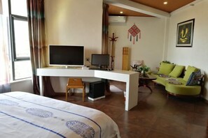 Una habitación de hotel con cama, escritorio con televisor, sofá y un adorno en la pared.