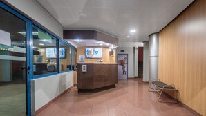 A reception area with a counter, a glass door, and a wooden wall. - Apart Hotel Elite  (Santiago)
