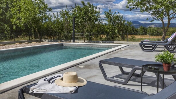 A poolside area with a pool, lounge chairs, a table with a hat and towel, and a potted plant. - Private Pool with Relaxing Nature View - Apt Mirna (Ripenda Verbanci)