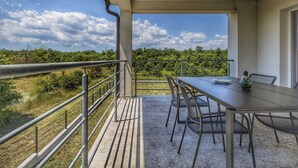 A balcony with a table and chairs, overlooking a lush landscape. - Private Pool with Relaxing Nature View - Apt Mirna (Ripenda Verbanci)