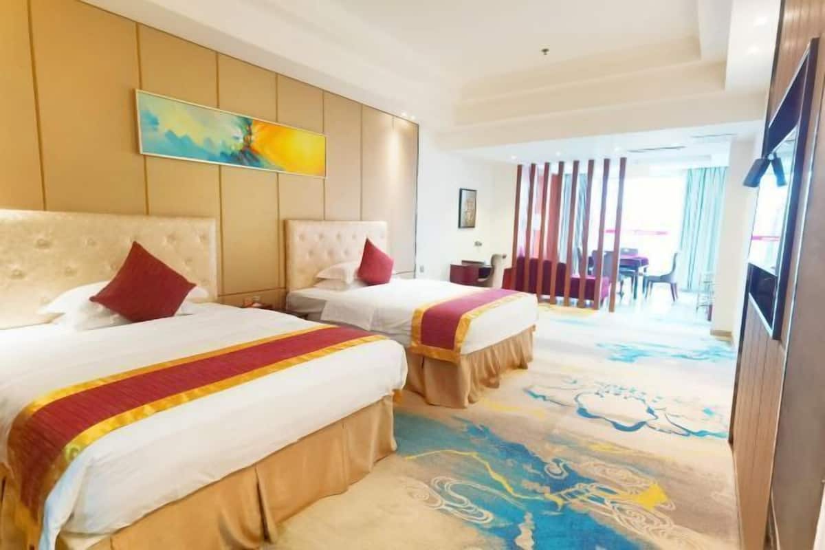 A hotel room with two beds, a large painting on the wall, and a view of the hotel lobby.