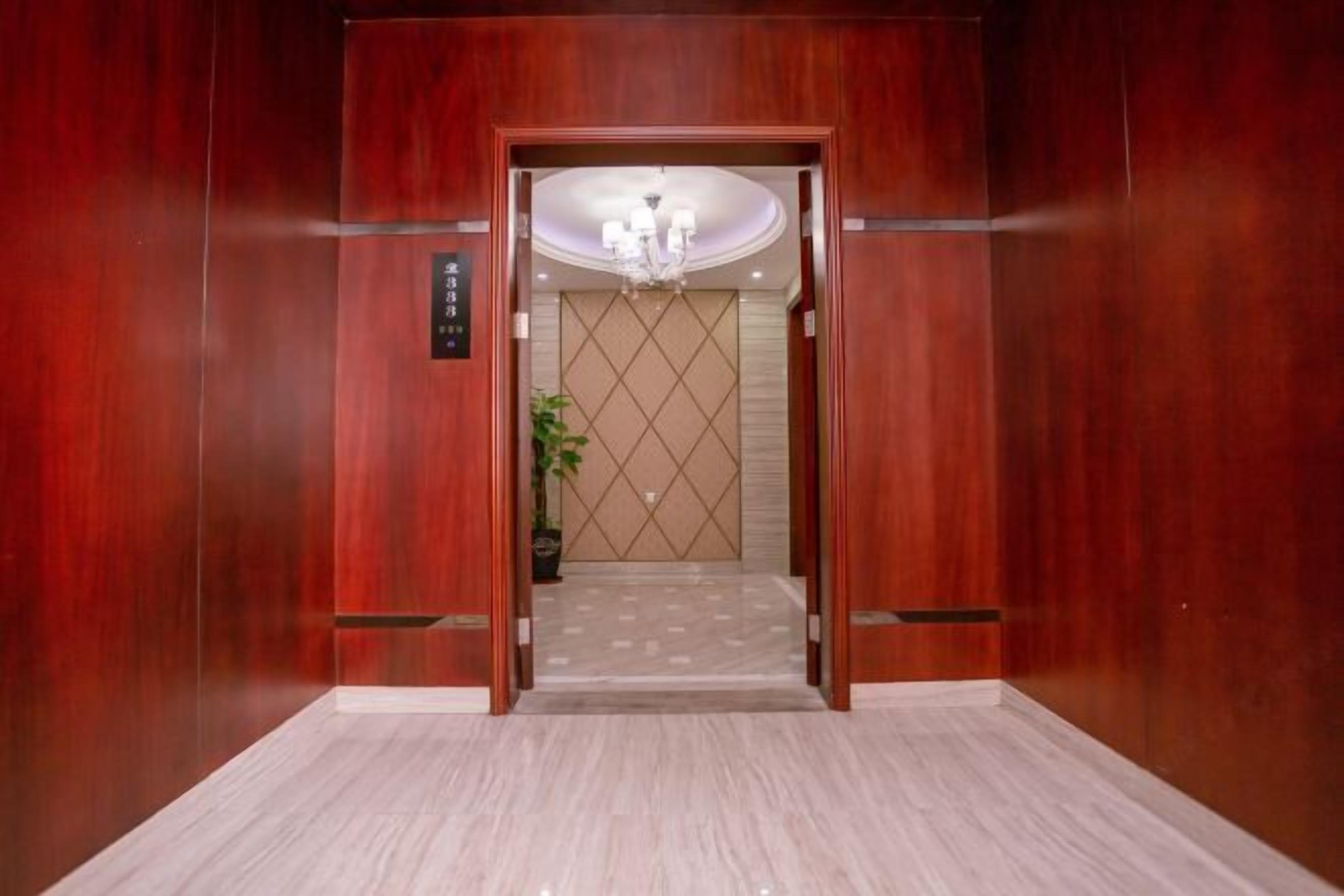 An elevator with a wooden finish, a chandelier, and a tiled floor.