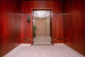 An elevator with a wooden finish, a chandelier, and a tiled floor. - Ruixia Business Hotel (Renhua)