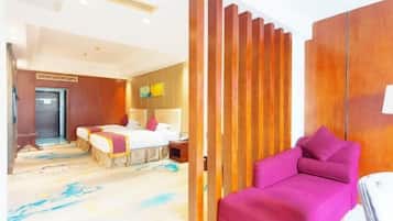 A hotel room with a bed, a pink sofa, a wooden partition, and a carpet with a blue pattern.