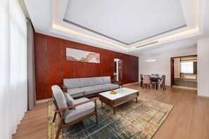 A modern living room with a sofa, coffee table, and a dining area with chairs and a table. - Ruixia Business Hotel (Renhua)