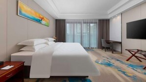 Une chambre d’hôtel avec un lit, un bureau, une chaise, une télévision et un tableau au mur.