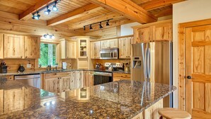 Una cocina amplia con armarios de madera, encimeras de granito y electrodomésticos de acero inoxidable, además de una isla grande.