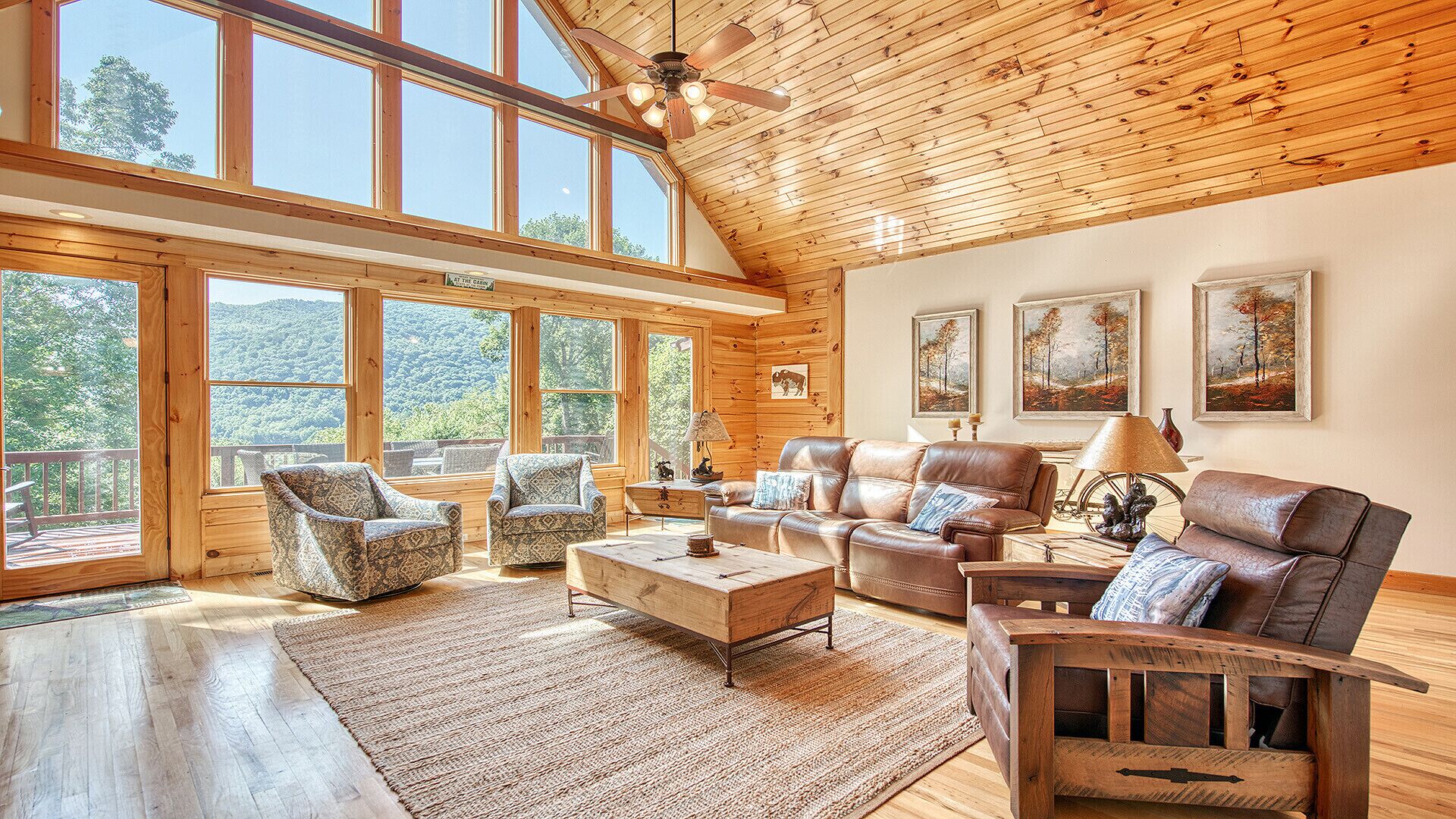 Amplia sala de estar con ventanas grandes, techo de madera y vistas al exterior.