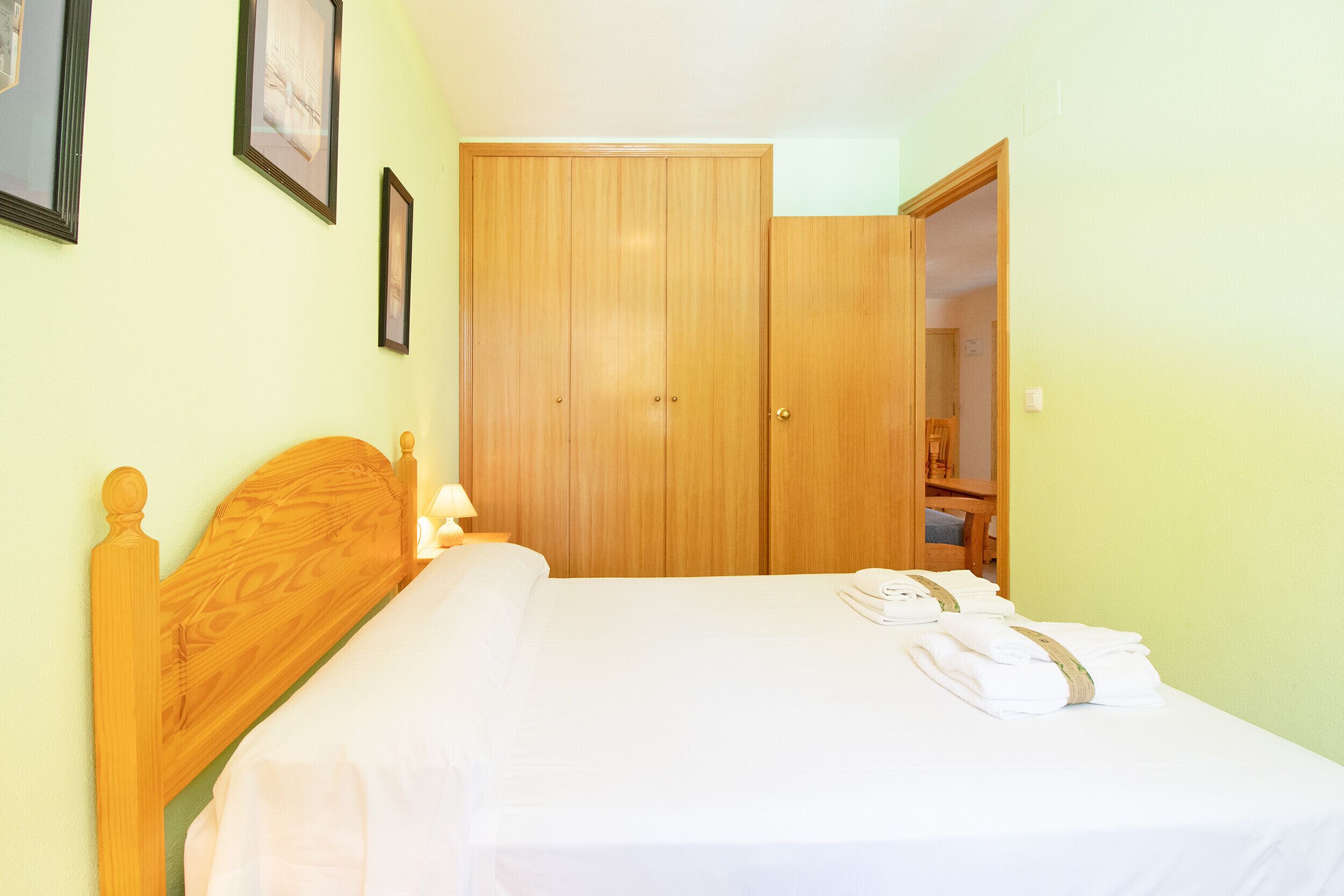 Un dormitorio con cabecero de madera, un armario grande y una cama bien hecha con toallas.