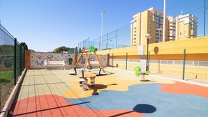 Une aire de jeux avec des équipements colorés et une zone délimitée par une clôture.