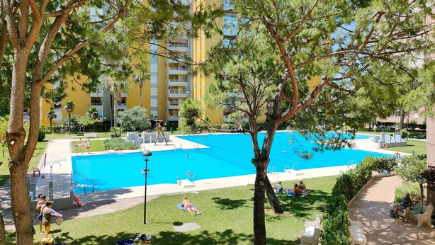 Une piscine entourée d’arbres et un bâtiment doté de balcons.